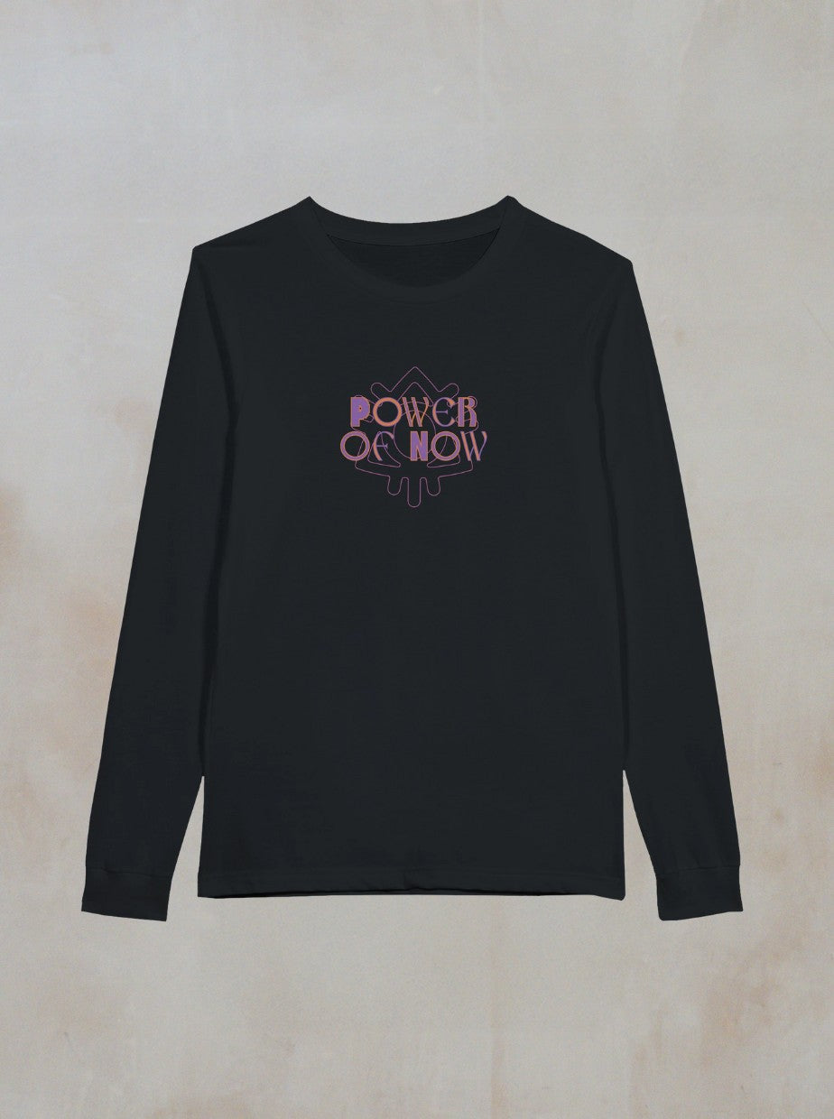 The Zephyr Long Sleeve by Boomtown Fair Shop is a black long sleeve tee featuring POWER OF NOW in purple and pink gradient text on the chest, shown on a light beige background—ideal as a festival top or your go-to Boomtown shirt.