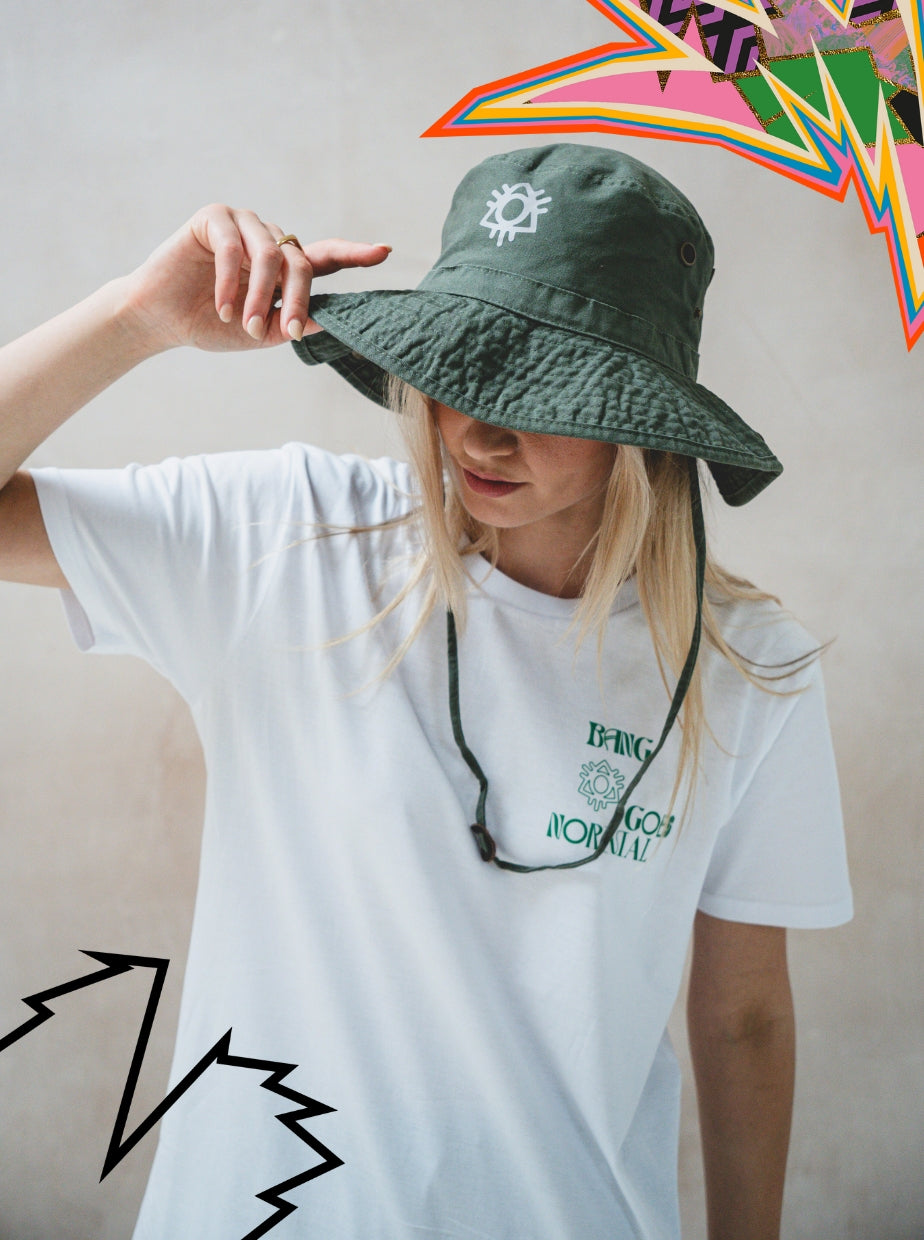 A person in a white T-shirt tilts down the 2025 Safari Hat Khaki, partially hiding their face. Colorful, abstract graphic shapes appear in the top right and bottom left corners of the image.