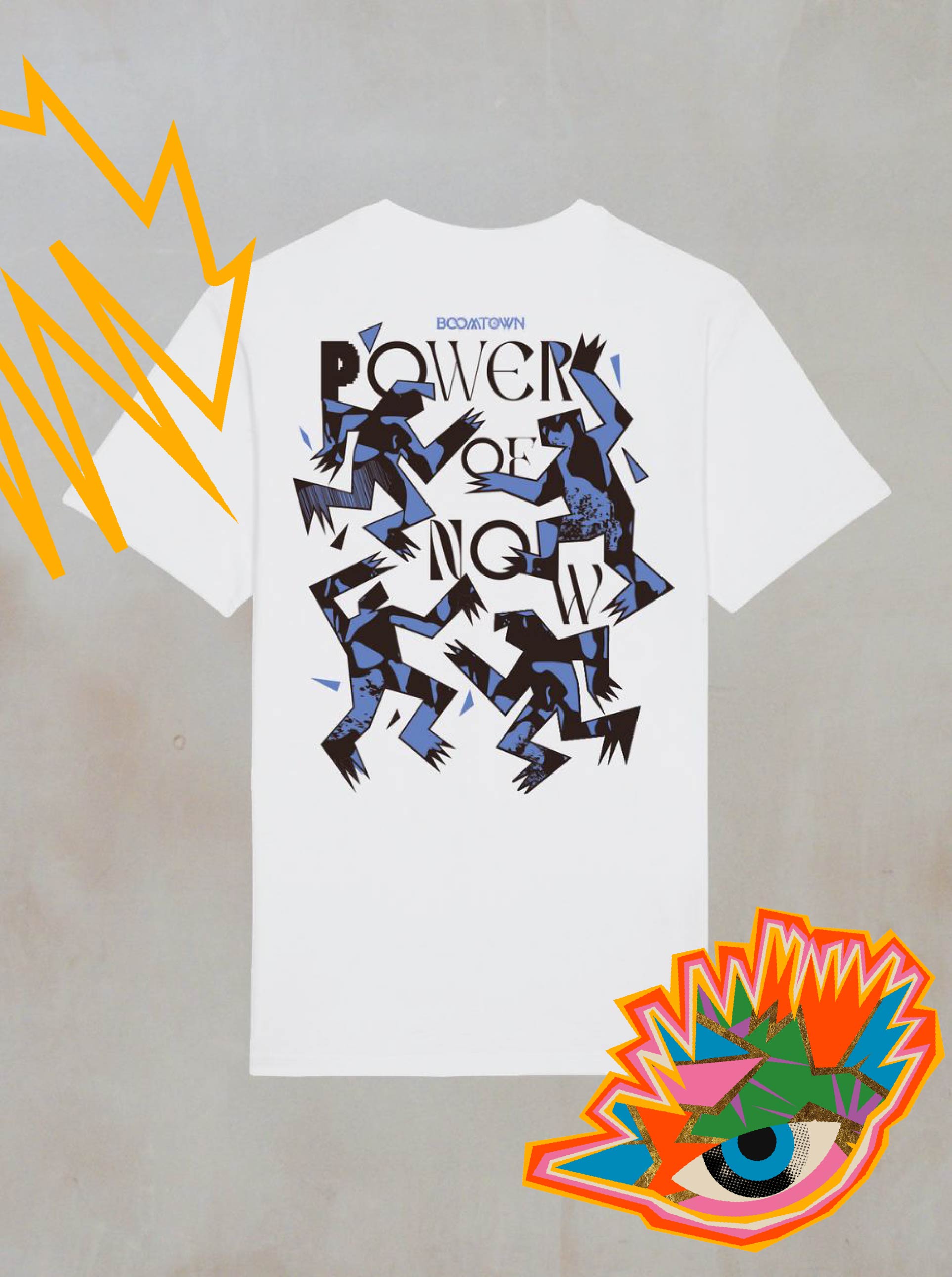 The Motion T-Shirt by Boomtown Fair Shop is a white organic cotton tee featuring abstract blue and black figures and POWER OF NOW text on the back—ideal for explorers who love minimalist style. Displayed on a gray surface with colorful graphics.