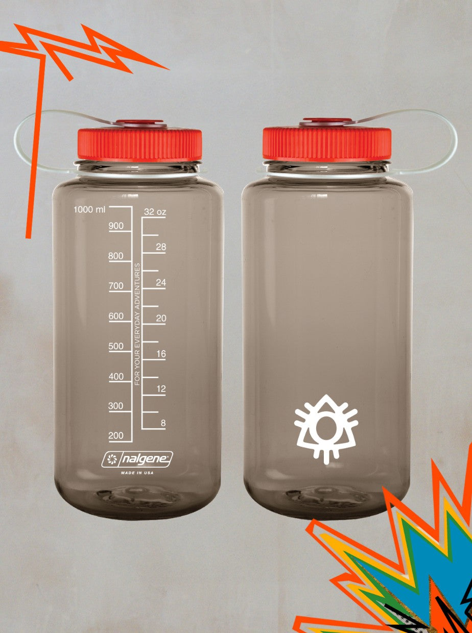 Two Boomtown x Nalgene Evergreen Reusable Water Bottles from Boomtown Fair Shop are shown side by side—one with measurement markings, one with a white sun graphic. Both have red lids, and colorful abstract shapes accent the corners.